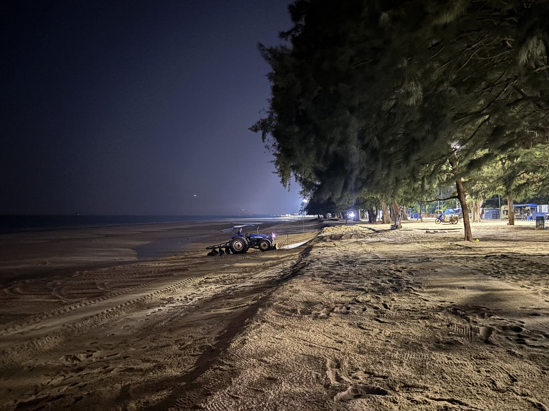 Cha-Am beach at night with a beach tractor parked under casuarina trees, Thailand