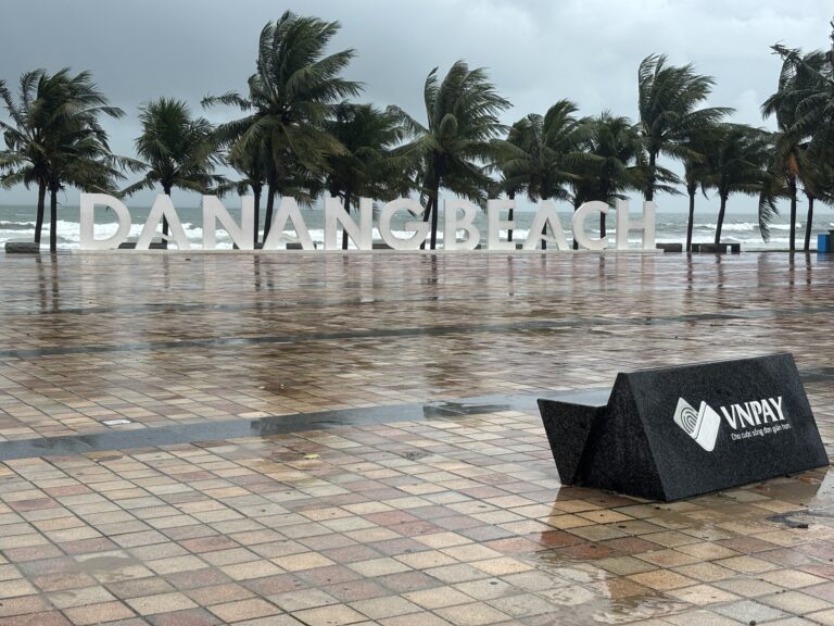 DA NANG BEACH sign in front of palm trees on a wet, overcast day on the central Vietnamese coast