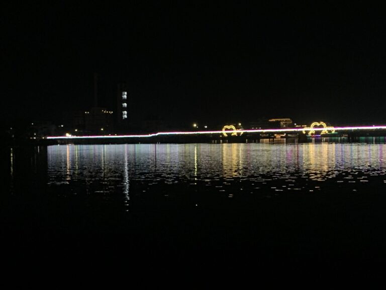 Kampot riverfront at night with the neon-lit bridge reflecting in the Prek Kampong Bay River