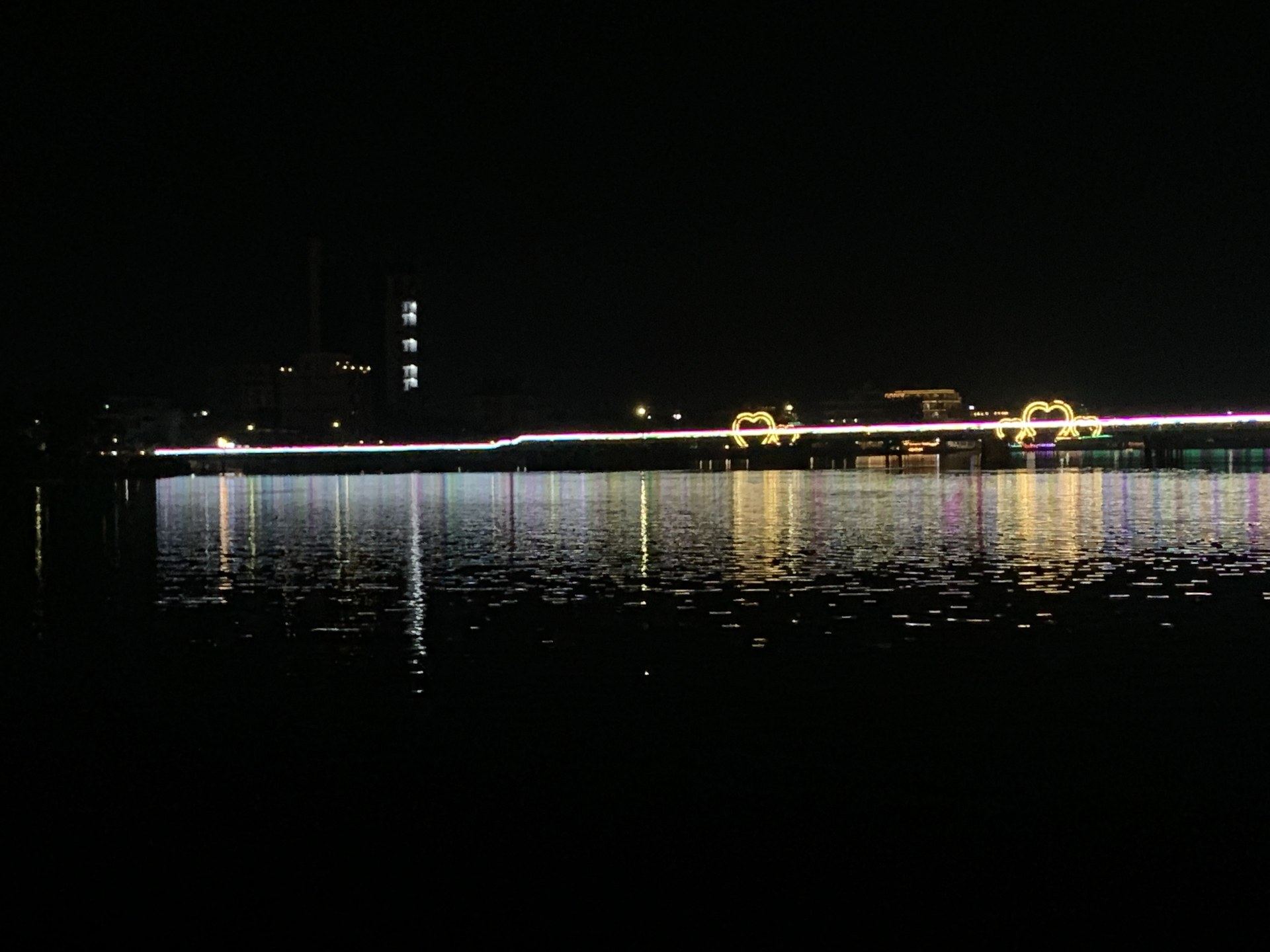 Kampot riverfront at night with the neon-lit bridge reflecting in the Prek Kampong Bay River