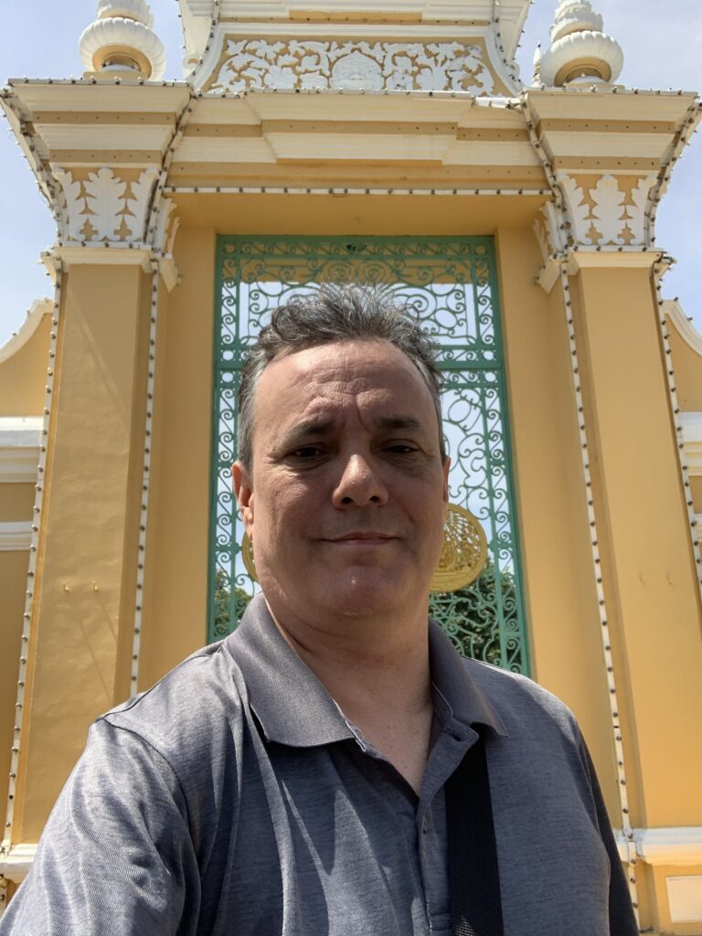 Sebastien Brousseau in front of the gold-and-white Royal Palace gates in Phnom Penh, Cambodia
